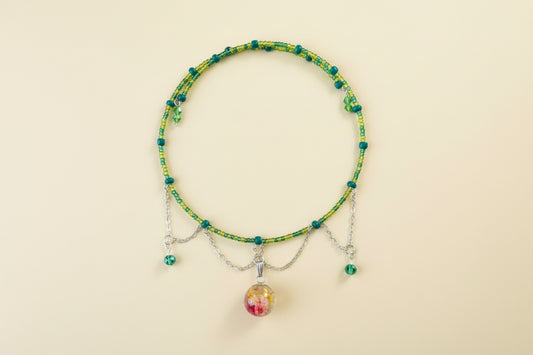 Beaded memory wire necklace with a colorful bead pendant on a beige background