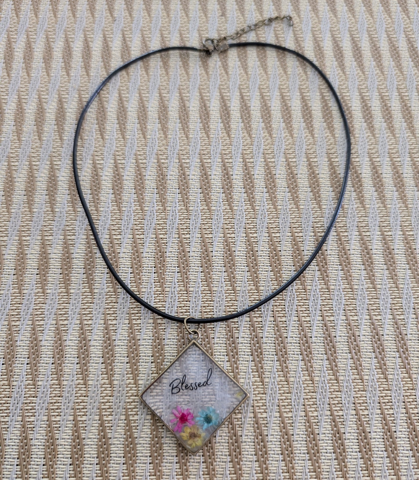 Elevate any outfit with our stunning 18 inches resin and flowers bronze diamond pendant necklace. The intricate Blessed design adds a touch of elegance, while the black 2mm leather cord provides a bold contrast. Lightweight and versatile, perfect for any occasion.