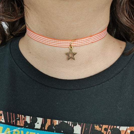 Add a touch of elegance and playfulness to your outfit with this stunning orange and white ribbon choker necklace. The gold star charm adds a touch of whimsy and the perfect amount of sparkle. Perfect for any occasion, this necklace is a must-have for any fashion lover!