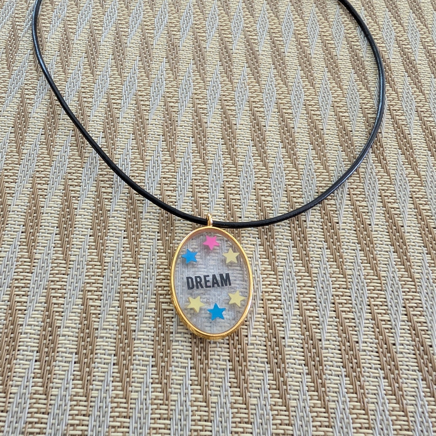 Indulge in the dreamy beauty of our 18 inch resin and stars gold oval pendant necklace. The stunning design is complemented by a 2mm black leather cord and adjustable extension chain. Weighing only 0.2 oz, it's lightweight and comfortable to wear. Elevate your style with this unique and charming accessory.