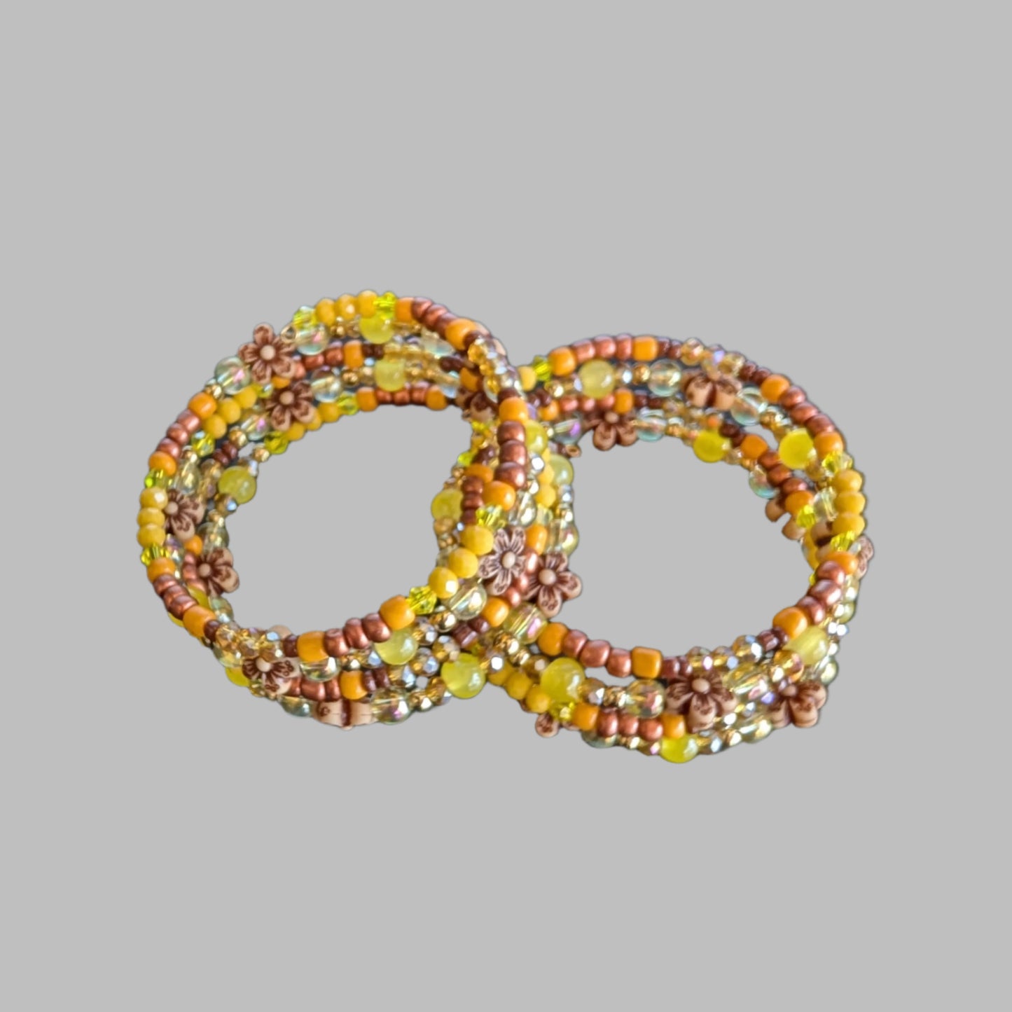 Brighten your style with this stunning memory wire bracelet featuring four coils of vibrant yellow beads accented by yellow and bronze spacer beads. Its flexible design ensures a comfortable fit for any wrist, while the floral-inspired arrangement adds a cheerful, handcrafted touch. Perfect for elevating everyday outfits with a splash of sunny elegance and subtle metallic charm.