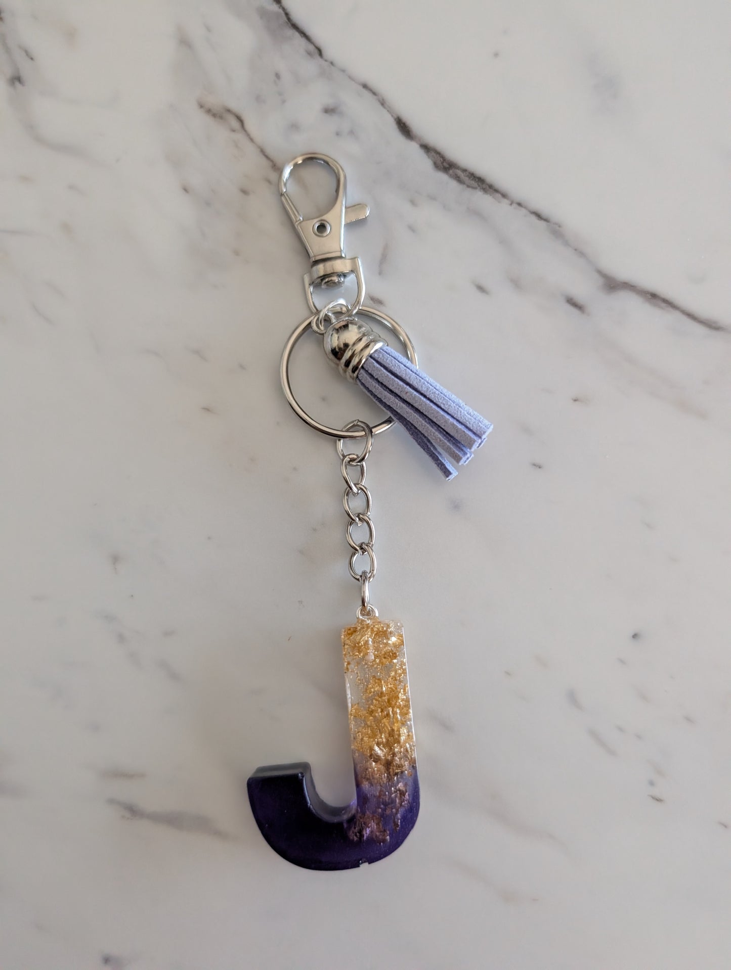 Keychain with a letter 'J' design on a marble surface