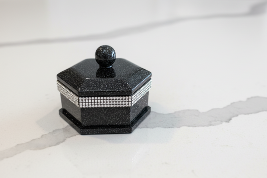 Black hexagonal container with a lid on a white surface