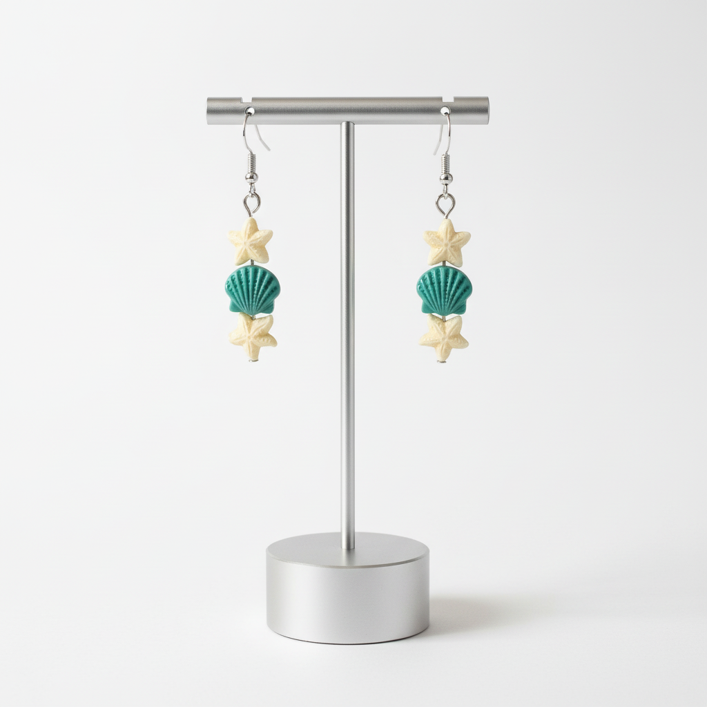 A pair of earrings with starfish and sea shell designs on silver hooks.