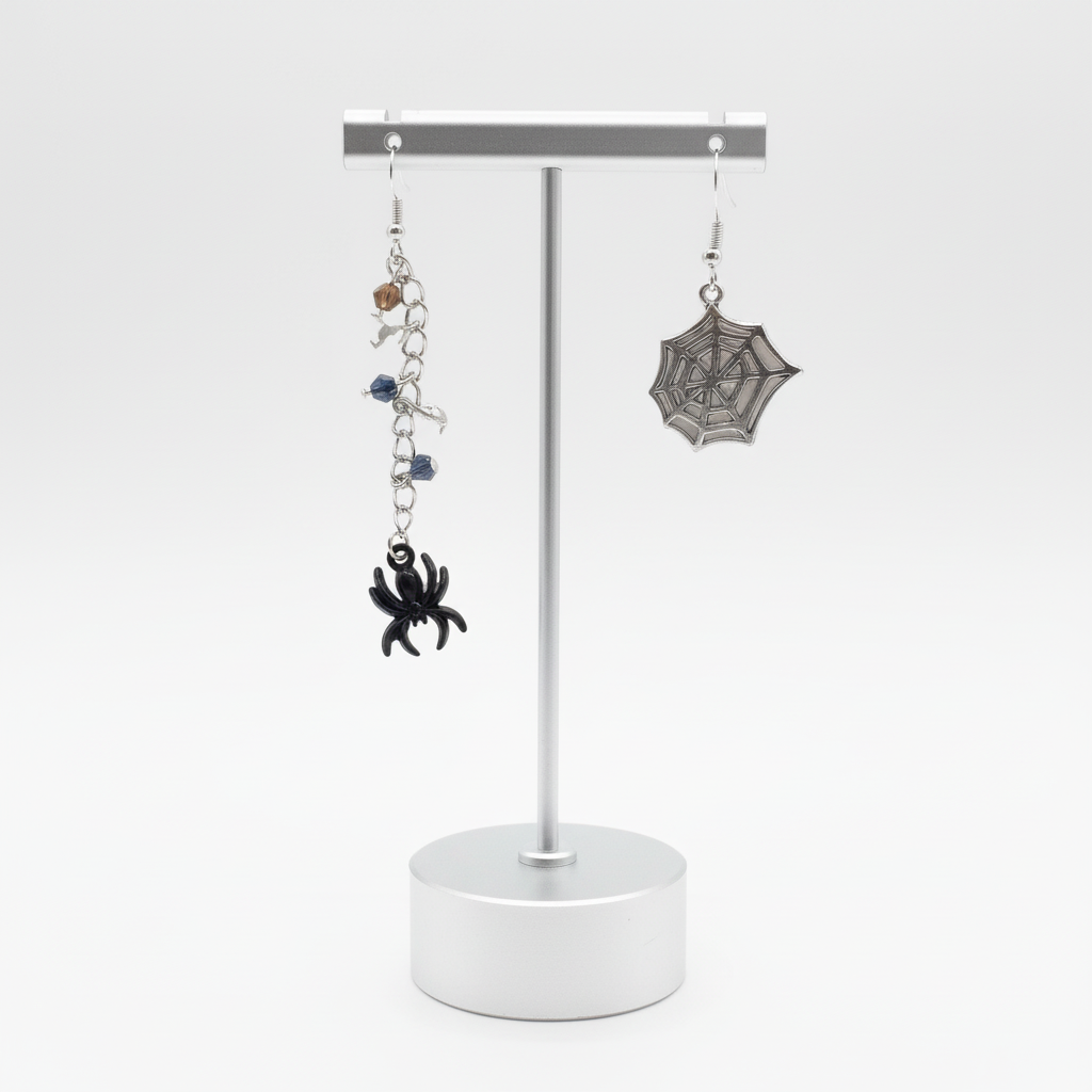 A pair of earrings featuring a black spider on a chain with beads, and a silver spiderweb on the hook.