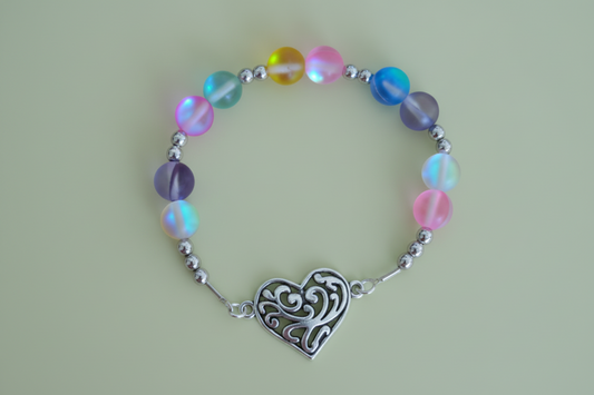 Bracelet with multicolored beads and a silver heart charm on a green background
