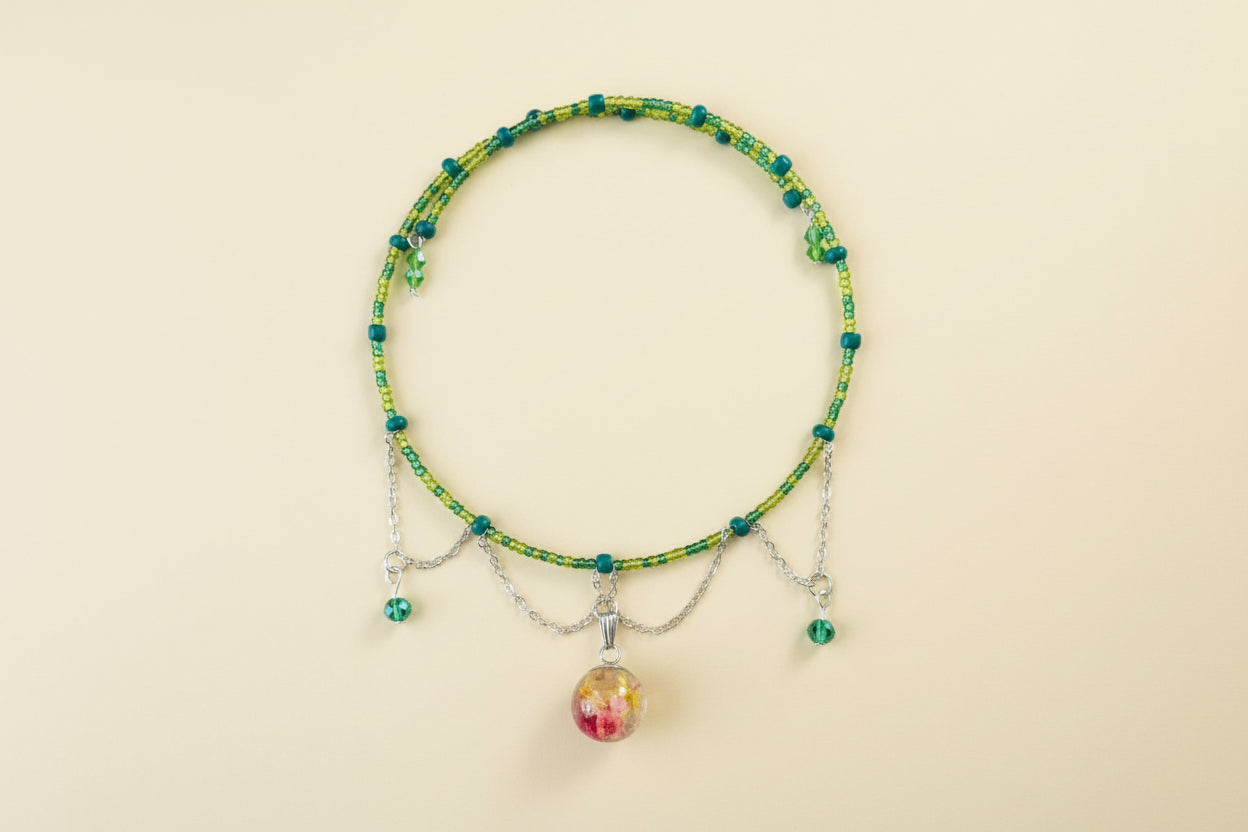 Beaded memory wire necklace with a colorful bead pendant on a beige background