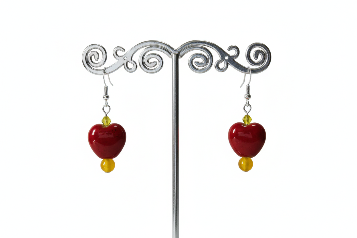 A pair of chunky heart-shaped bead earrings with yellow and red colors and crystal beads on a silver hook.