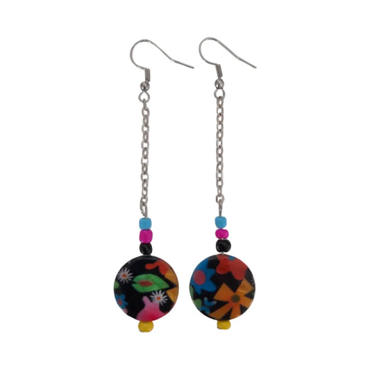 A pair of earrings featuring a colorful floral disc shell bead on a silver chain with drop hooks.