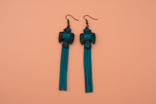 A pair of teal tassel earrings with charm on hooks.