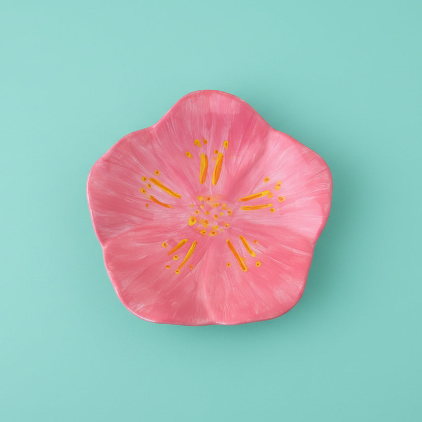 Pink flower petal with yellow center on a teal background