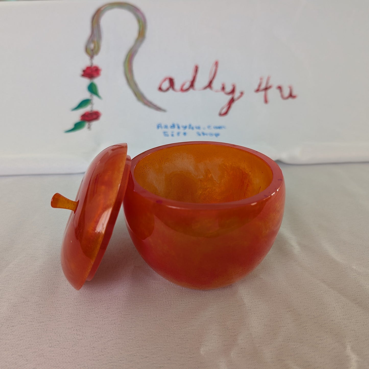 hand crafted with epoxy resin..

Epoxy resin is typically smooth, rigid, and non-porous, similar to a hard plastic or glass.

Knickknack - Resin apple trinket with lid