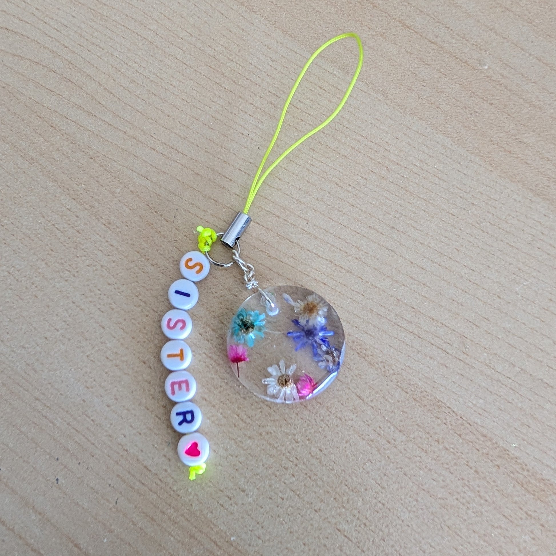 Spice up your phone with this charming resin charm, adorned with real dried flowers and beads. The 3.75 inch length adds a touch of flair to any device. (It's like a bouquet, but for your phone!)

Phone charm - Resin charm with dried flowers and beads