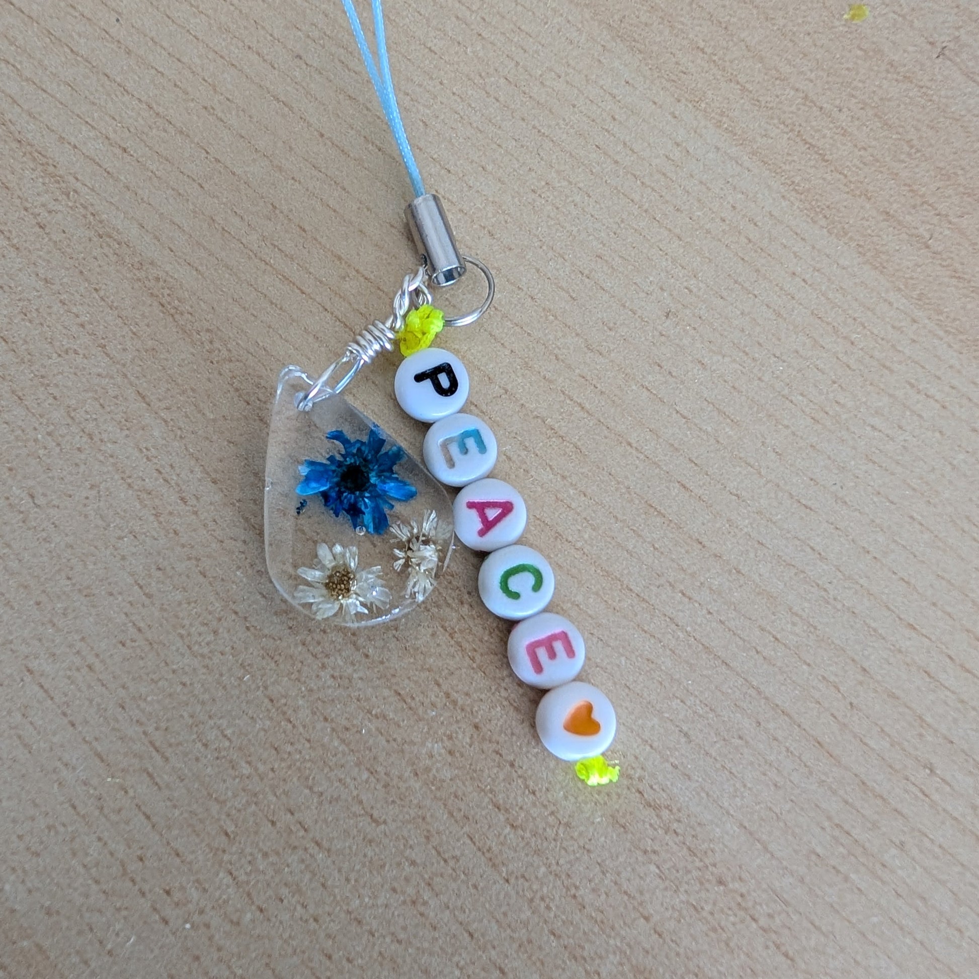 Spice up your phone with this charming resin charm, adorned with real dried flowers and beads. The 3.75 inch length adds a touch of flair to any device. (It's like a bouquet, but for your phone!)

Phone charm - Resin charm with dried flowers and beads