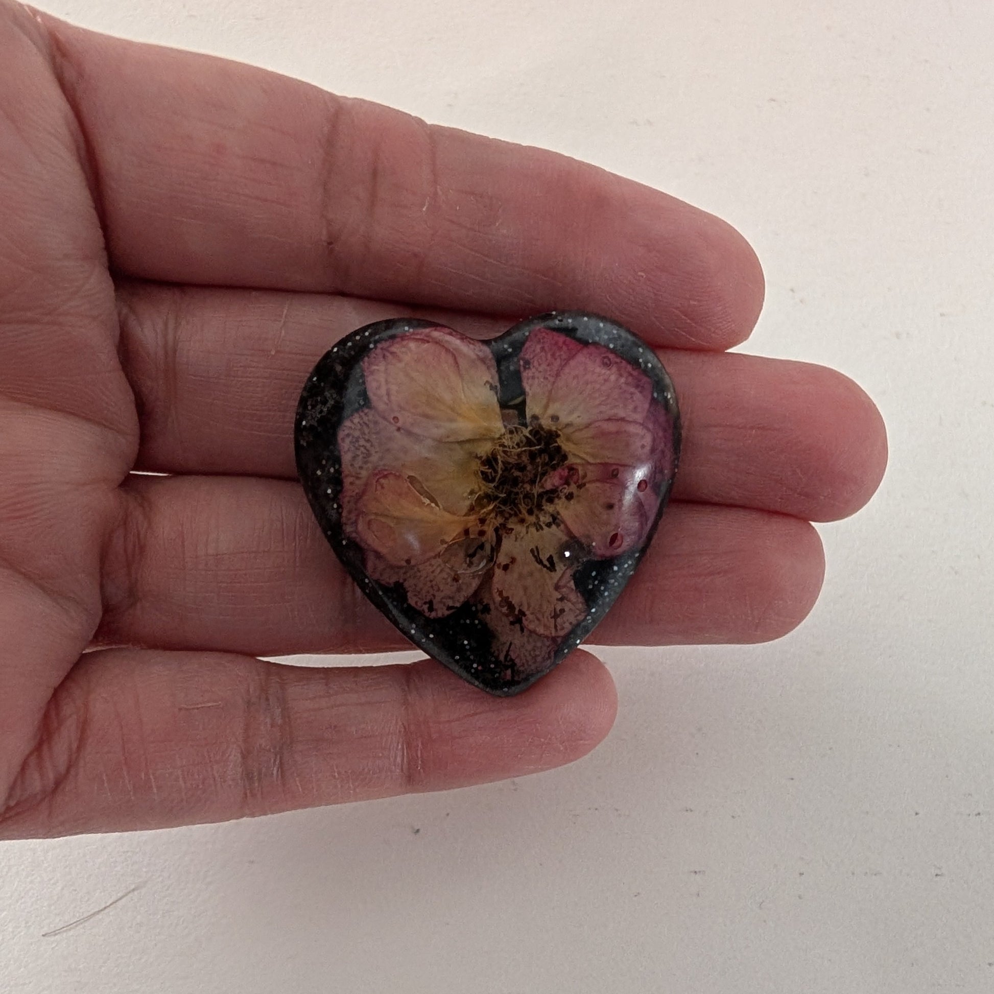 Add a touch of whimsy to any outfit with our 3D dried flower in resin pin. The stunning silver butterfly clutch ensures secure and easy attachment. Let this pin be your new go-to accessory for an elevated and playful look!