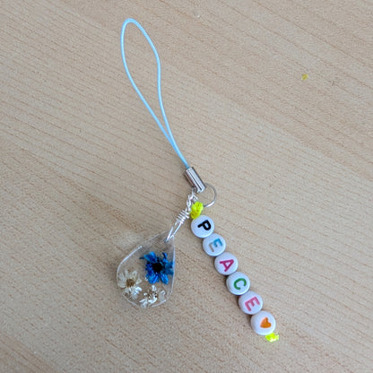 Spice up your phone with this charming resin charm, adorned with real dried flowers and beads. The 3.75 inch length adds a touch of flair to any device. (It's like a bouquet, but for your phone!)

Phone charm - Resin charm with dried flowers and beads