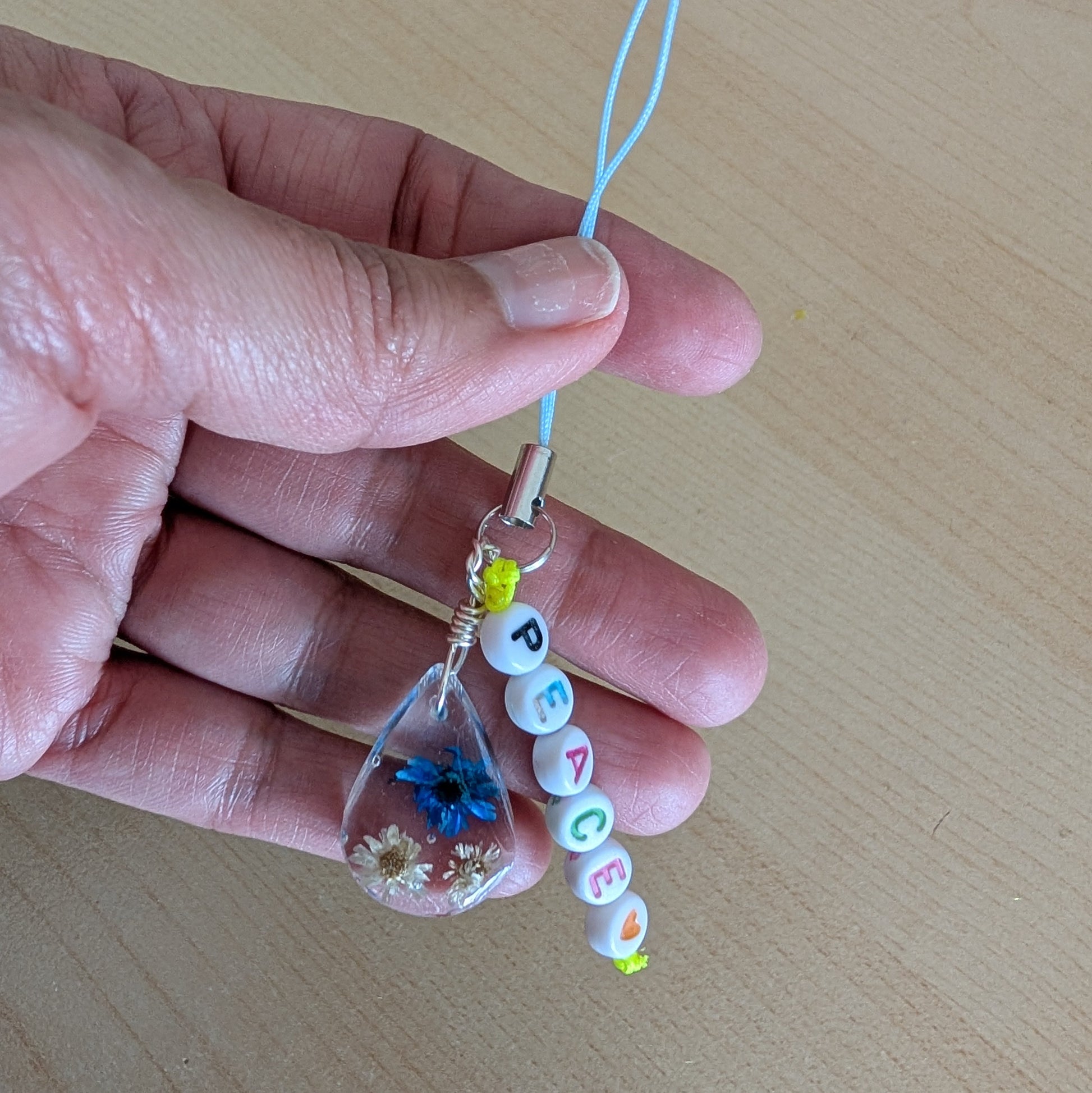 Spice up your phone with this charming resin charm, adorned with real dried flowers and beads. The 3.75 inch length adds a touch of flair to any device. (It's like a bouquet, but for your phone!)

Phone charm - Resin charm with dried flowers and beads