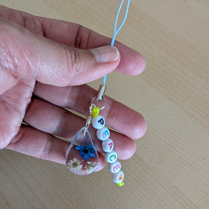 Spice up your phone with this charming resin charm, adorned with real dried flowers and beads. The 3.75 inch length adds a touch of flair to any device. (It's like a bouquet, but for your phone!)

Phone charm - Resin charm with dried flowers and beads