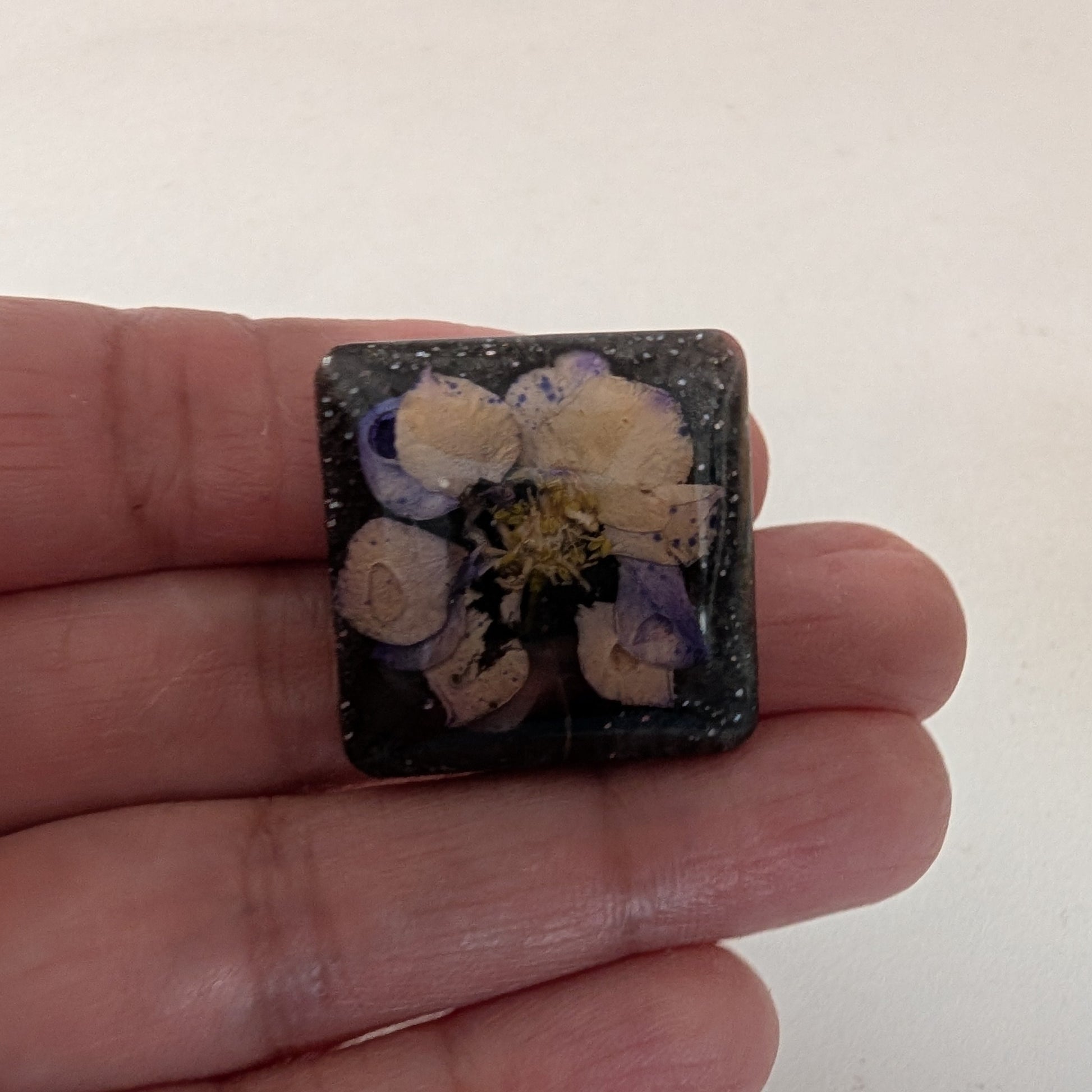 Add a touch of whimsy to any outfit with our 3D dried flower in resin pin. The stunning silver butterfly clutch ensures secure and easy attachment. Let this pin be your new go-to accessory for an elevated and playful look!