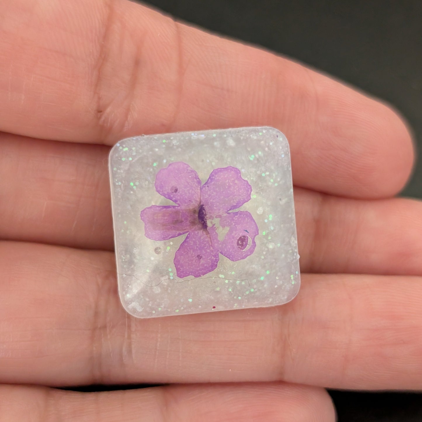 Add a touch of nature to your outfit with our Pin - 3D dried flower resin pin. The intricate design and 3D effect will surely catch everyone's eye. With the sturdy silver butterfly clutch, your pin will stay securely in place. Elevate your style with this unique and beautiful accessory.