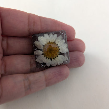 Add a touch of whimsy to any outfit with our 3D dried flower in resin pin. The stunning silver butterfly clutch ensures secure and easy attachment. Let this pin be your new go-to accessory for an elevated and playful look!