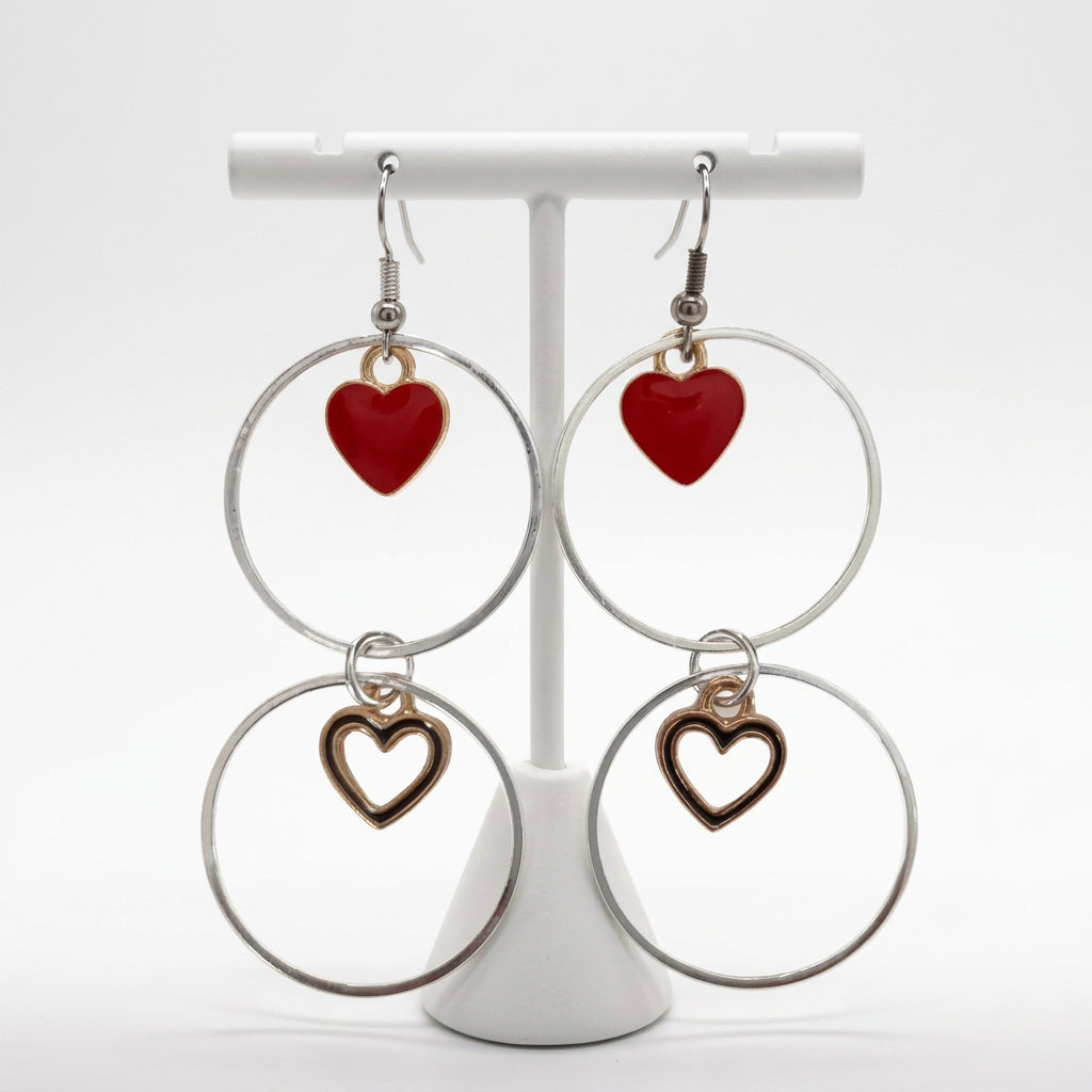 A pair of silver hoop earrings, one with a solid gold plated heart and one with a hollow gold plated heart.