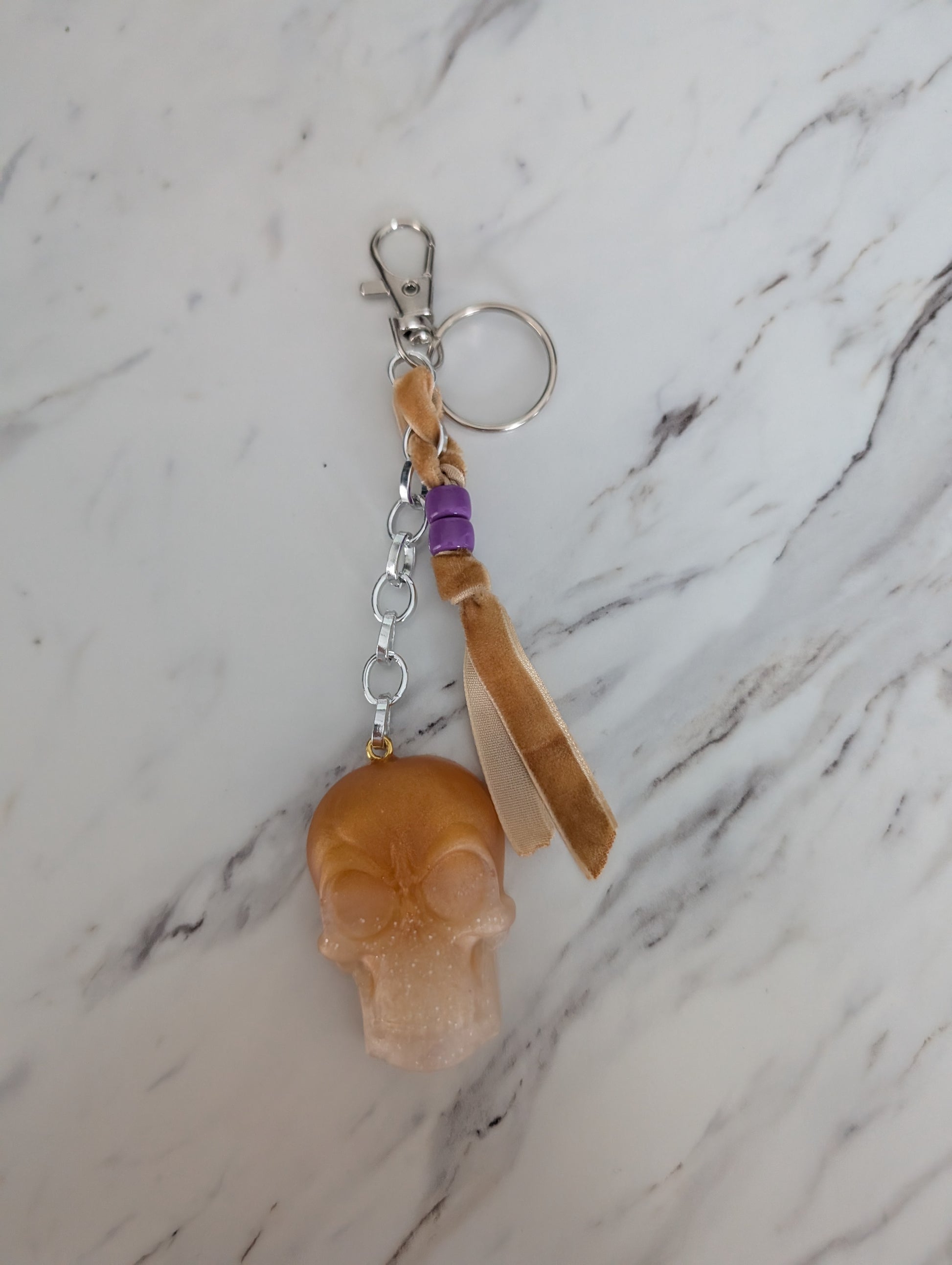 Skull-shaped keychain with a strap on a marble surface