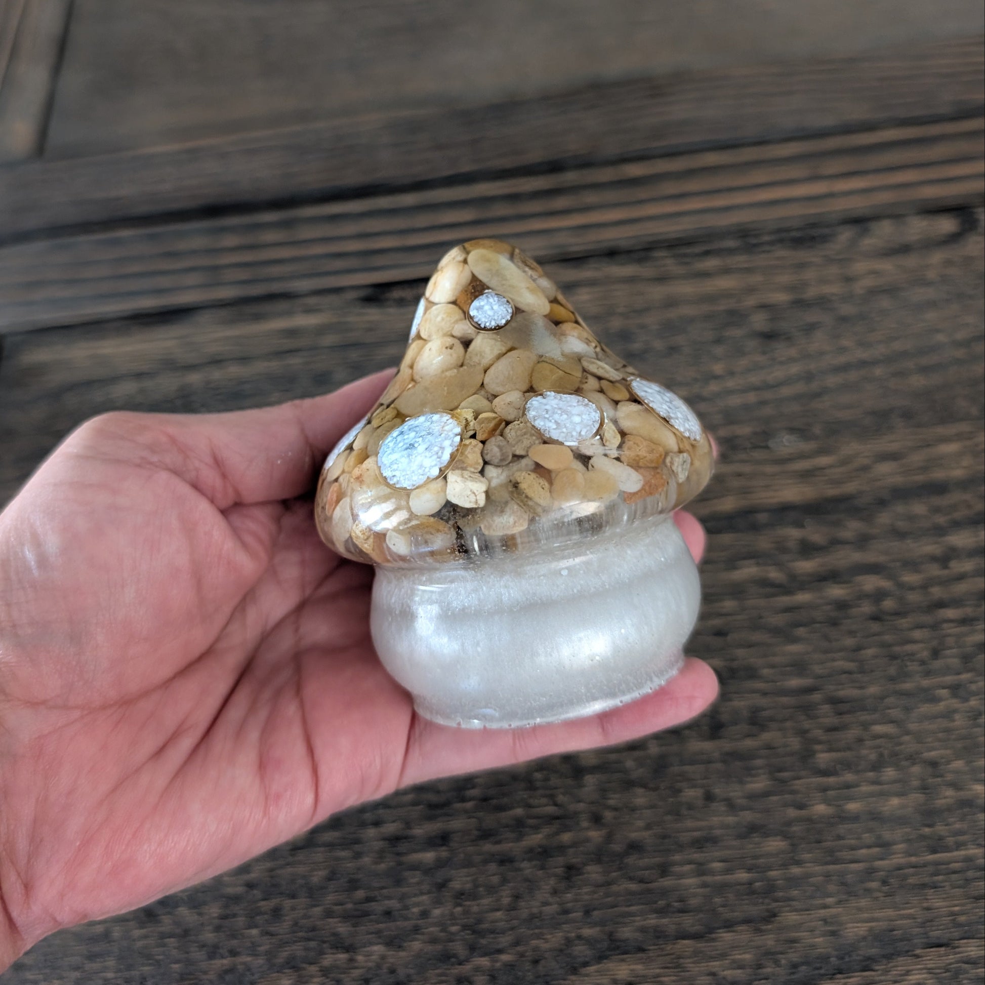 Hand holding a mushroom trinket with a wooden background