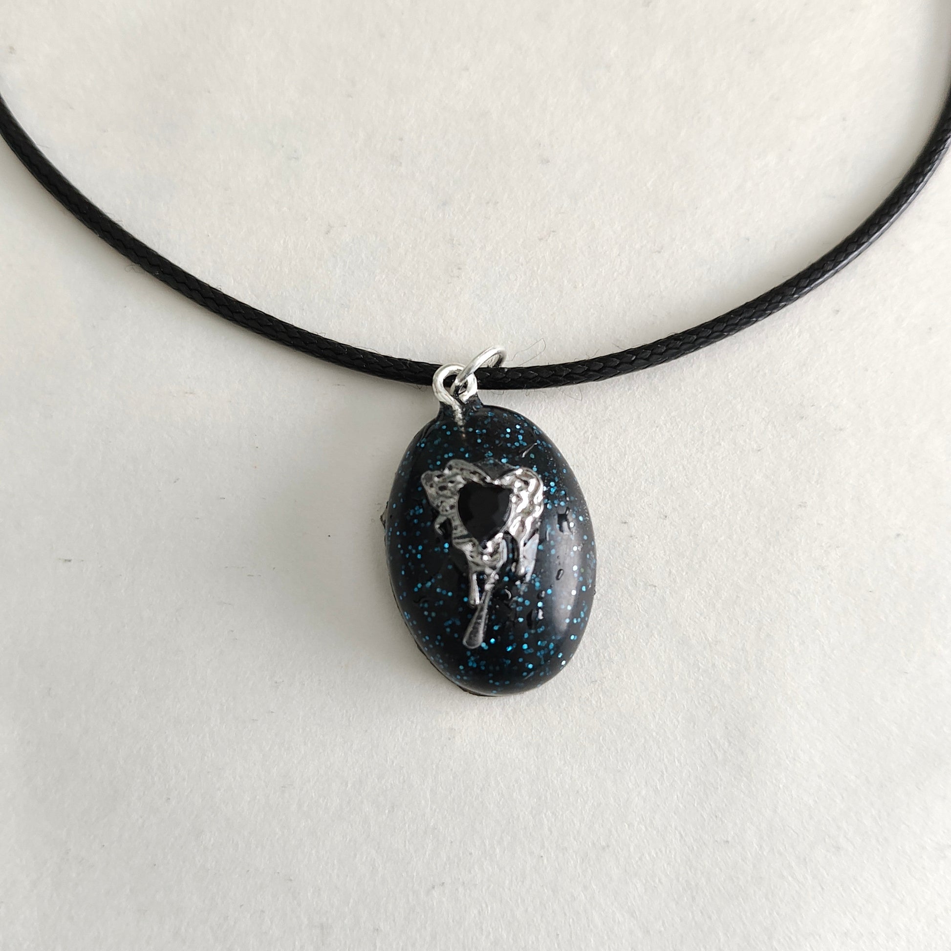 This stunning necklace features a 17.5 inch black waxed cord that is both sleek and durable. The resin and silver charm pendant adds a touch of elegance and charm to any outfit. An effortless way to make a statement.