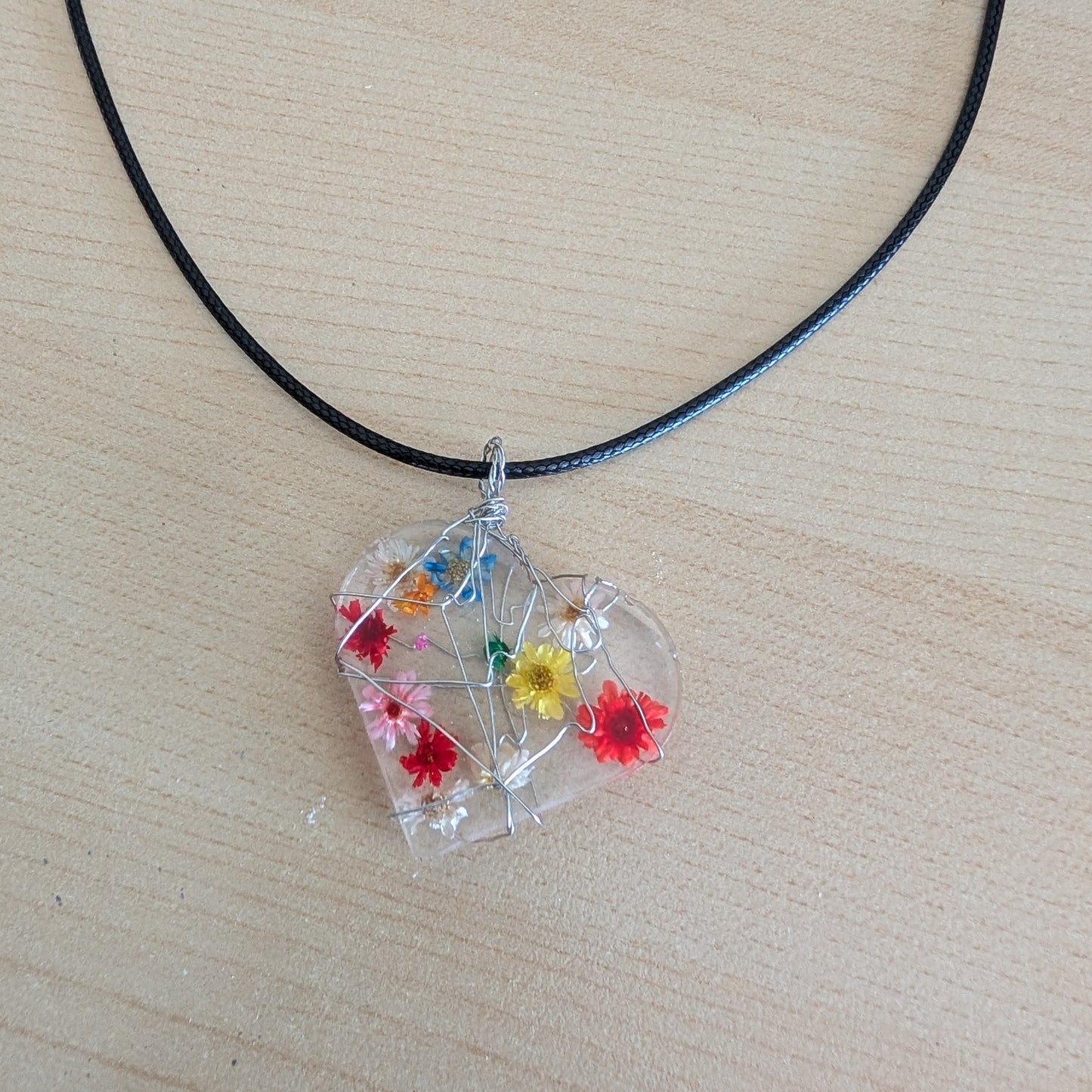 This stunning necklace features a heart-shaped pendant made of clear resin and real dried flowers, delicately suspended on a black cord. Measuring at 17.5 inches (plus a 2-inch extension chain), this unique piece adds a touch of nature and charm to any outfit.

Necklace - 17.5 inches clear resin with dried flowers heart on black cord