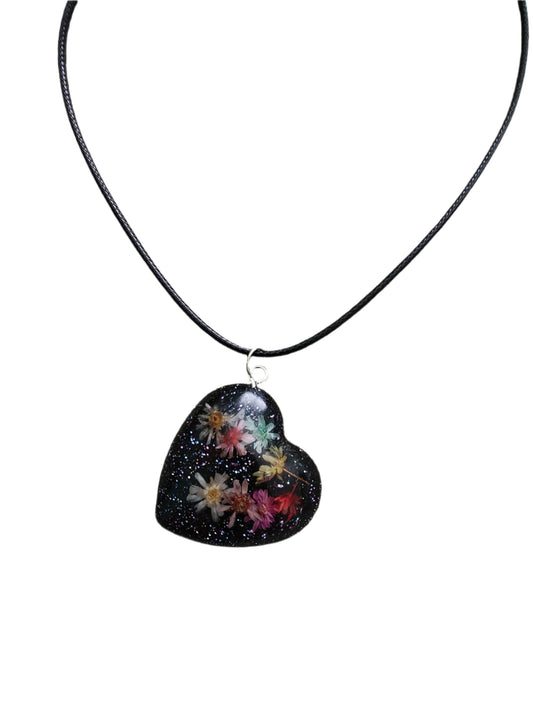 This stunning necklace features a 17.5 inch black waxed cord that is both sleek and durable. The resin with dried flowers pendant adds a touch of elegance and charm to any outfit. An effortless way to make a statement.