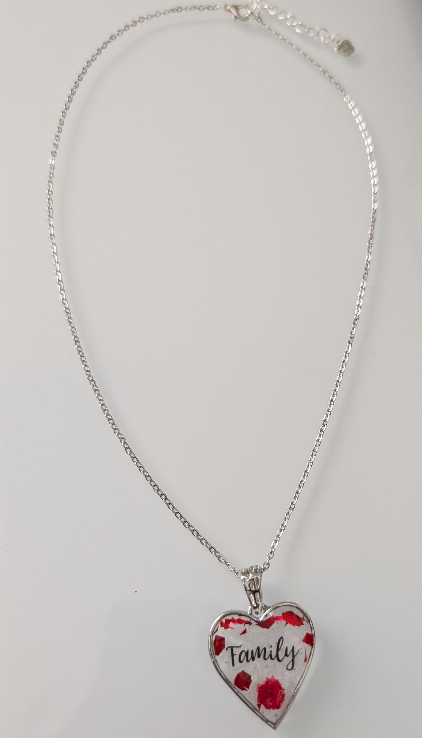 This stunning necklace features a 21-inch stainless steel cable link chain adorned with a beautiful family resin and flowers silver heart pendant. The perfect length for any outfit, with the option to add an additional 2 inches for the perfect fit. Show your love and style with this unique piece!

Necklace - 21 inches stainless steel cable link chain with a family resin and flowers silver heart pendant