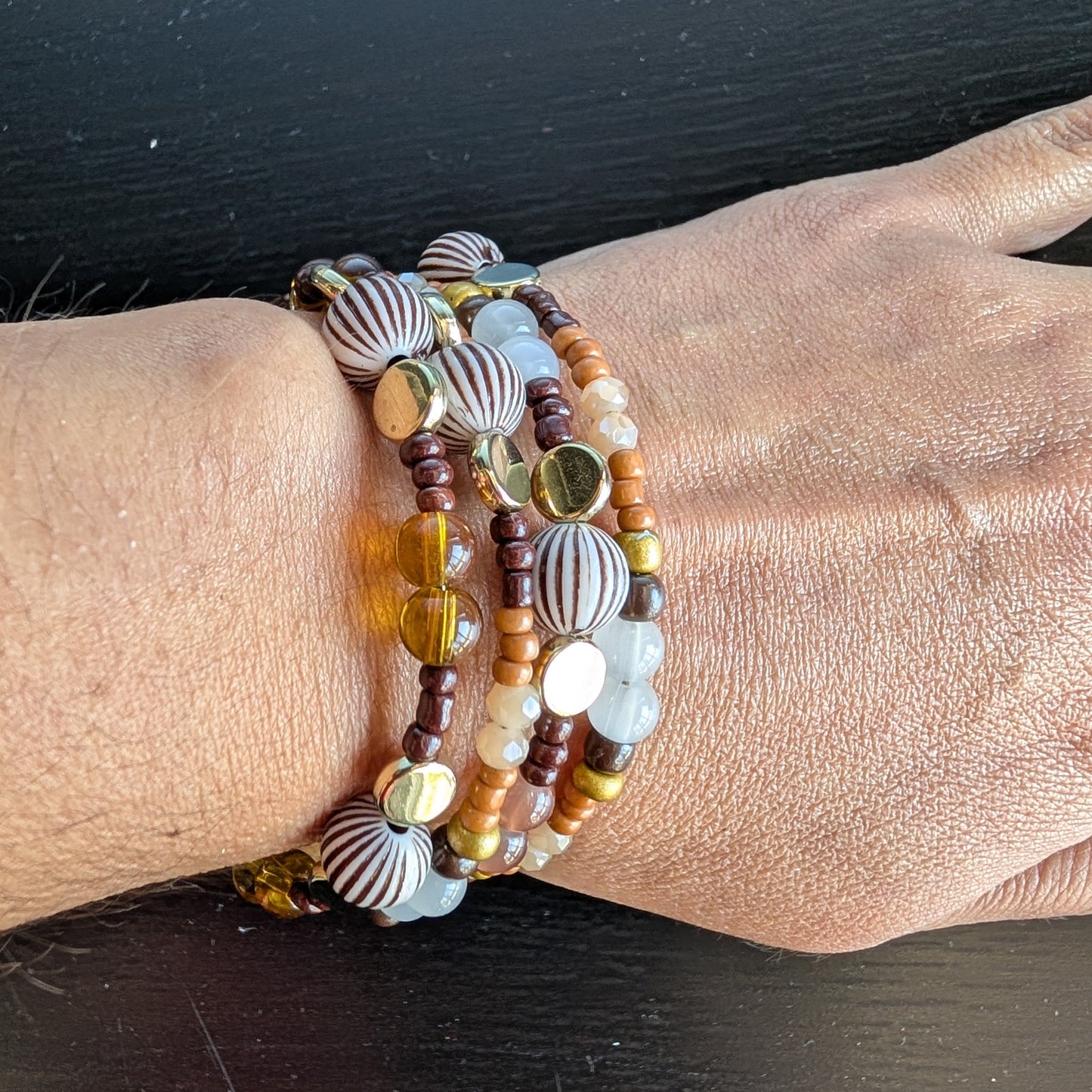 This elegant memory wire bracelet features four coils adorned with brown, white, and tan beads, complemented by gold, brown, and tan spacer beads. Its versatile color palette pairs effortlessly with any outfit, while the flexible design ensures a comfortable fit for all wrist sizes. Add a touch of sophistication and warmth to your look with this stylish accessory.