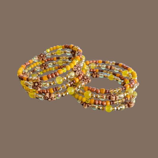 Brighten your style with this stunning memory wire bracelet featuring four coils of vibrant yellow beads accented by yellow and bronze spacer beads. Its flexible design ensures a comfortable fit for any wrist, while the floral-inspired arrangement adds a cheerful, handcrafted touch. Perfect for elevating everyday outfits with a splash of sunny elegance and subtle metallic charm.