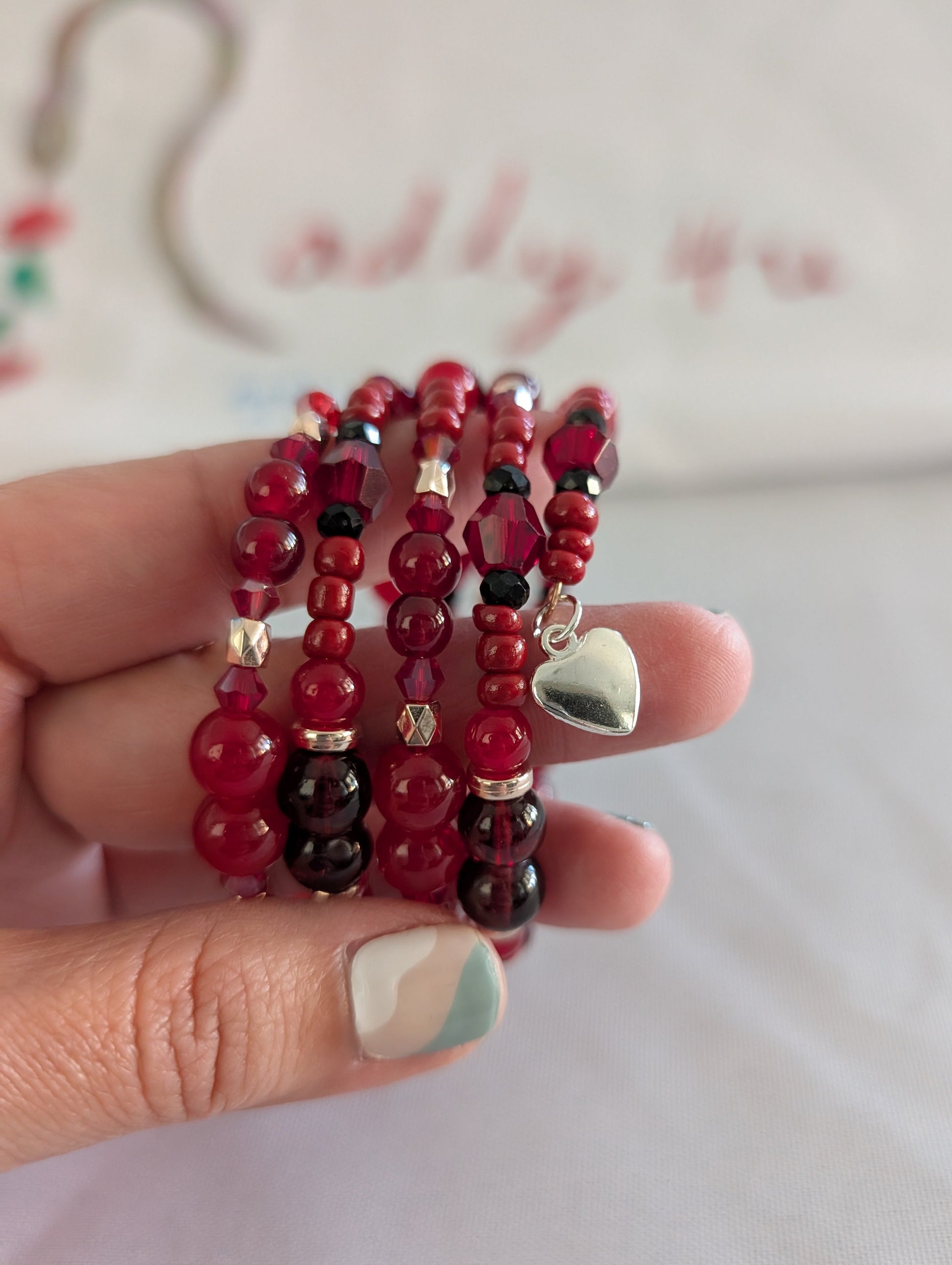 Elevate your everyday style with this stunning red memory wire bracelet, designed to make a lasting impression. Featuring a captivating mix of 8mm, 6mm, and 4mm red glass and crystal beads that catch the light beautifully, this piece combines elegance with versatility. Delicate gold spacer beads and vibrant red seed beads add intricate detail, while a charming silver heart pendant serves as the perfect finishing touch. The four-coil memory wire construction ensures a comfortable, secure fit that adapts to y