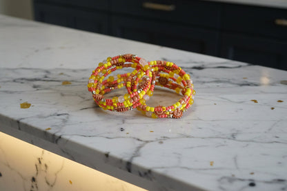 This vibrant memory wire bracelet features four coils adorned with yellow and sun beads, complemented by yellow, tan, and orange spacer beads. Its flexible design ensures a comfortable fit for any wrist size, making it an eye-catching accessory that brightens your look with warm, sunny hues. Perfect for adding a splash of color and effortless style to your everyday outfits.