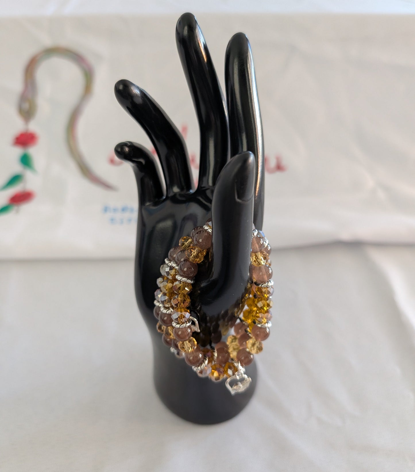 Express your heart with this warm and radiant elastic bracelet that combines rich brown and gold tones with timeless sentiment. Featuring 8mm brown and gold beads interspersed with sparkling crystal and glass accents, silver spacers, and a delicate silver heart charm, this piece speaks to both style and emotion. The elastic band stretches effortlessly to fit any wrist, requiring no clasps or adjustments—just slip it on and go. Weighing a comfortable 0.60 oz, it's substantial enough to feel quality yet light