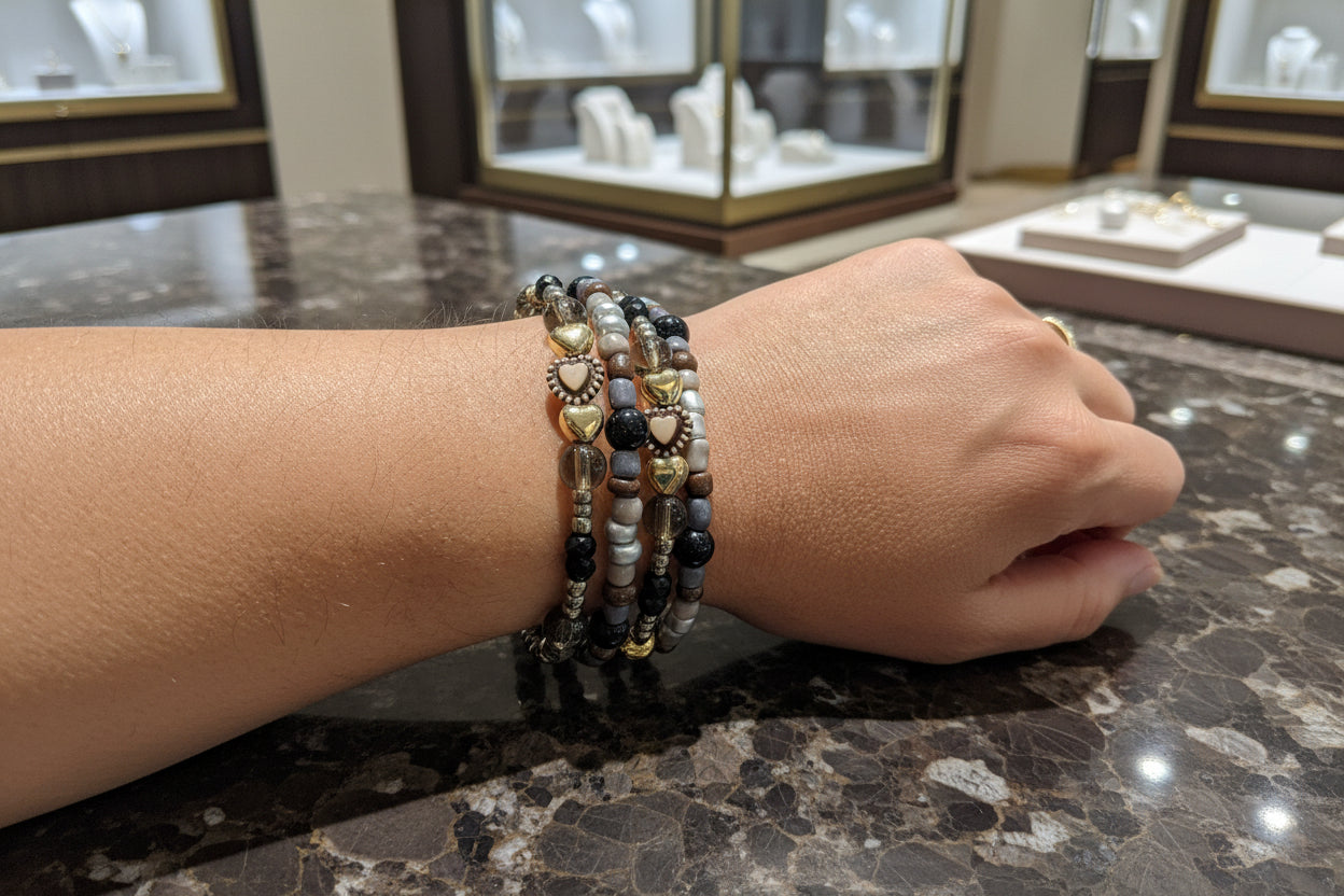 This elegant memory wire bracelet features four coils adorned with black and silver beads, accented by gold hearts and silver spacer beads. Its flexible design ensures a comfortable fit for any wrist size, making it a versatile accessory that adds a touch of sophistication to any outfit. Perfect for gifting or personal wear, this bracelet combines style and ease effortlessly.