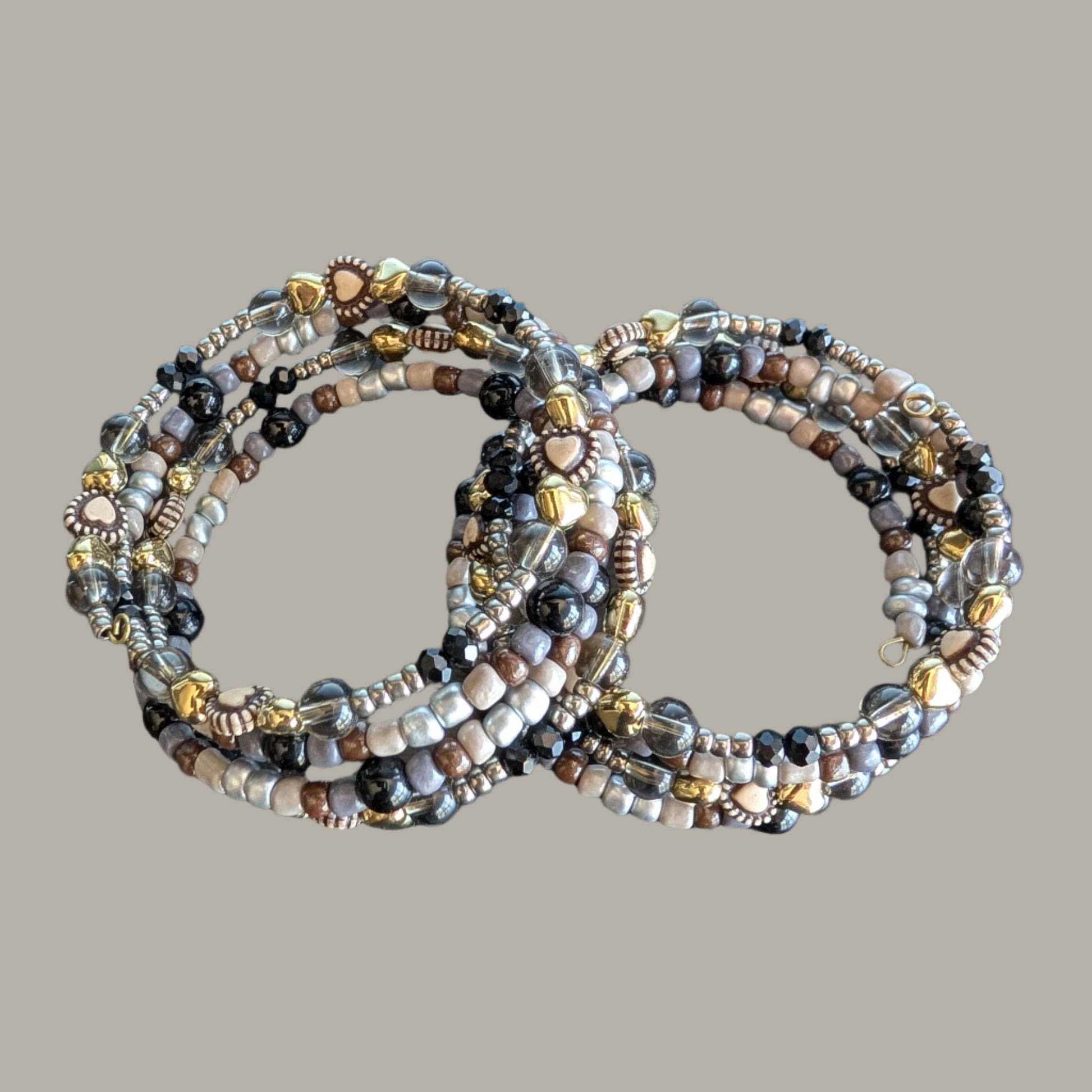 This elegant memory wire bracelet features four coils adorned with black and silver beads, accented by gold hearts and silver spacer beads. Its flexible design ensures a comfortable fit for any wrist size, making it a versatile accessory that adds a touch of sophistication to any outfit. Perfect for gifting or personal wear, this bracelet combines style and ease effortlessly.