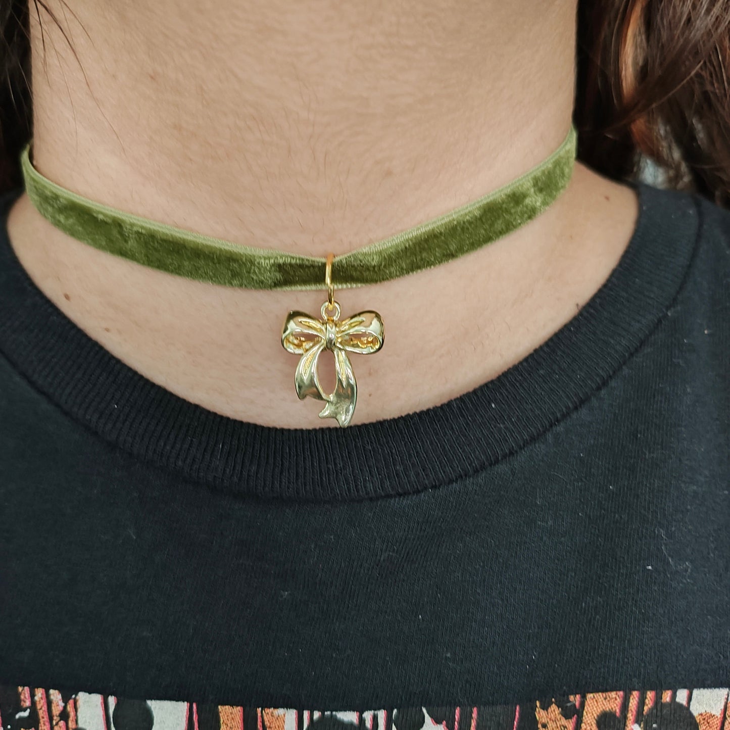 This stunning necklace features an olive green velvet ribbon that elegantly wraps around your neck, accented by a delicate gold bow charm. The soft texture of the ribbon and the eye-catching charm create a beautiful and sophisticated look. Perfect for adding a touch of class to any outfit!