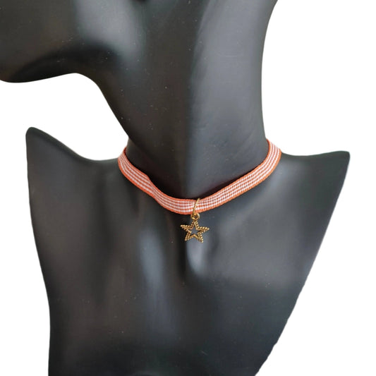 Add a touch of elegance and playfulness to your outfit with this stunning orange and white ribbon choker necklace. The gold star charm adds a touch of whimsy and the perfect amount of sparkle. Perfect for any occasion, this necklace is a must-have for any fashion lover!