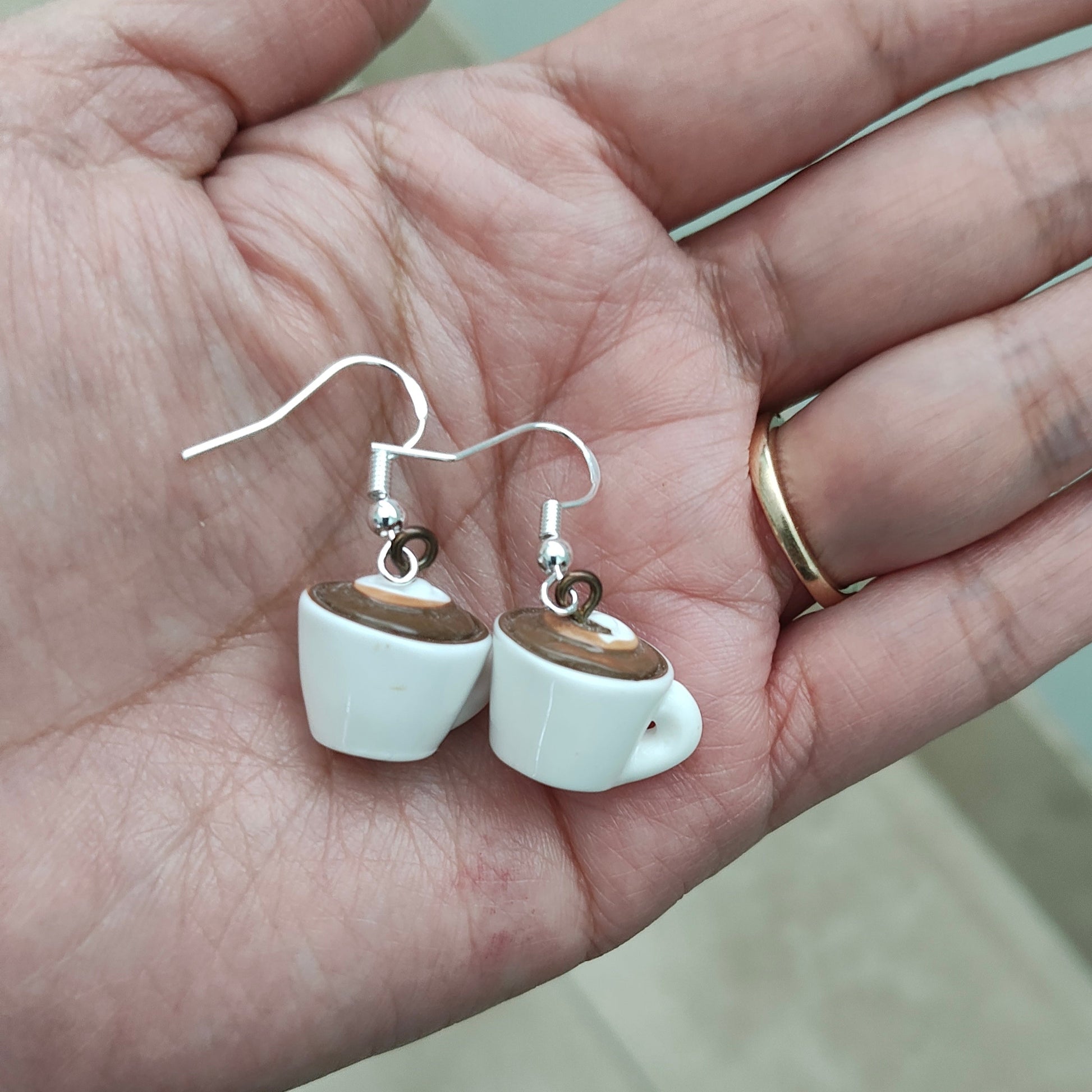 Add a touch of whimsy to your outfit with these coffee mug charm earrings. Made with a porcelain mug on a silver hook, these earrings are approximately 1.25 inches long and weigh 0.16 oz. Perfect for the coffee lover in your life!