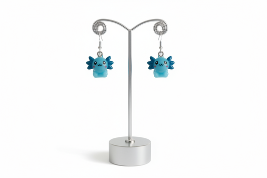 Blue axolotl character earrings on a silver stand against a white background