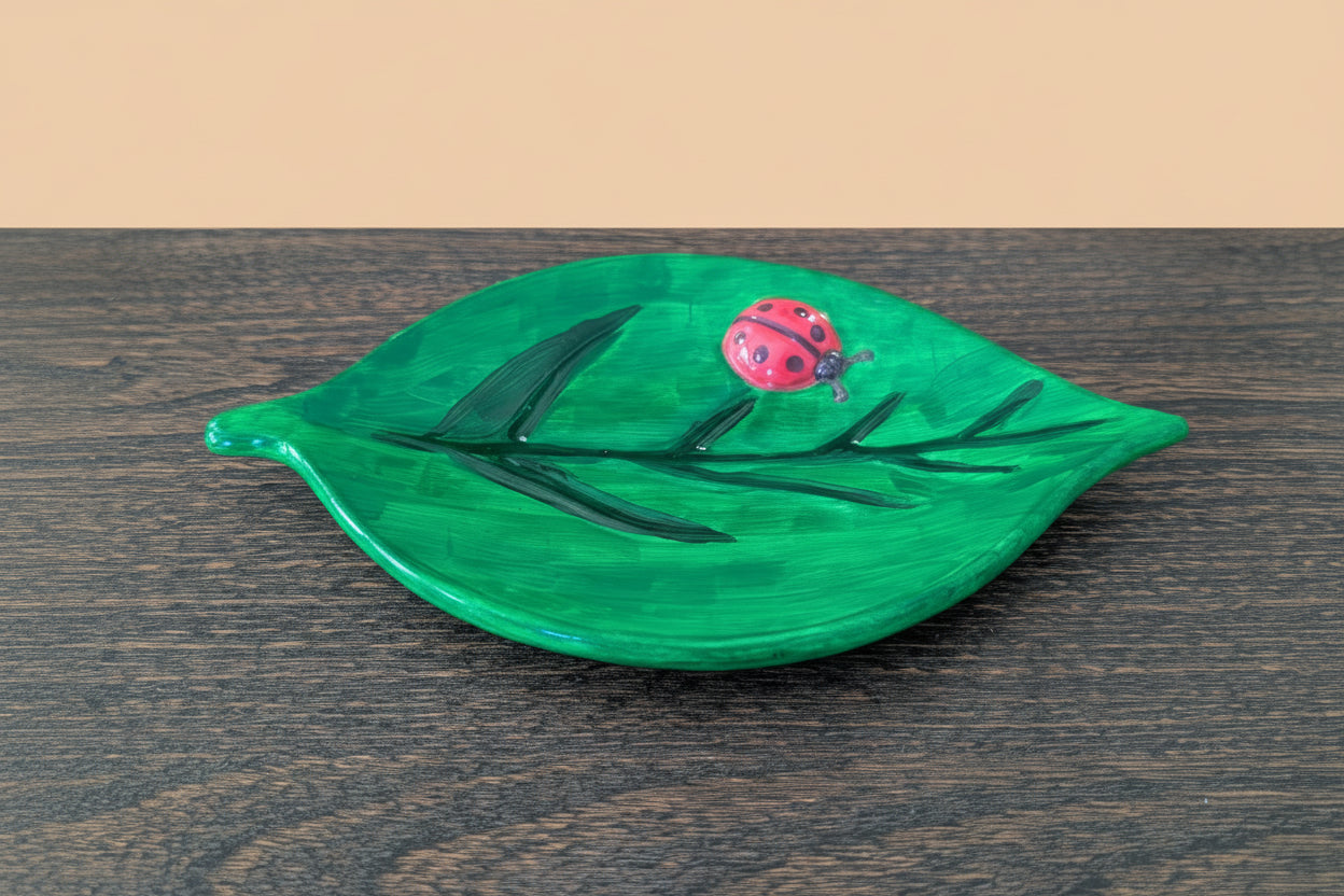 Handmade leaf-shaped plate with a ladybug design on a wooden surface