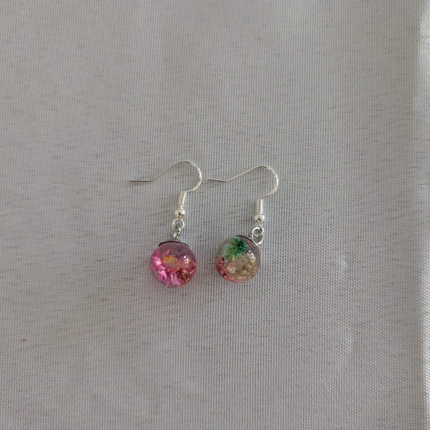 Pair of earrings with colorful beads on a gray background
