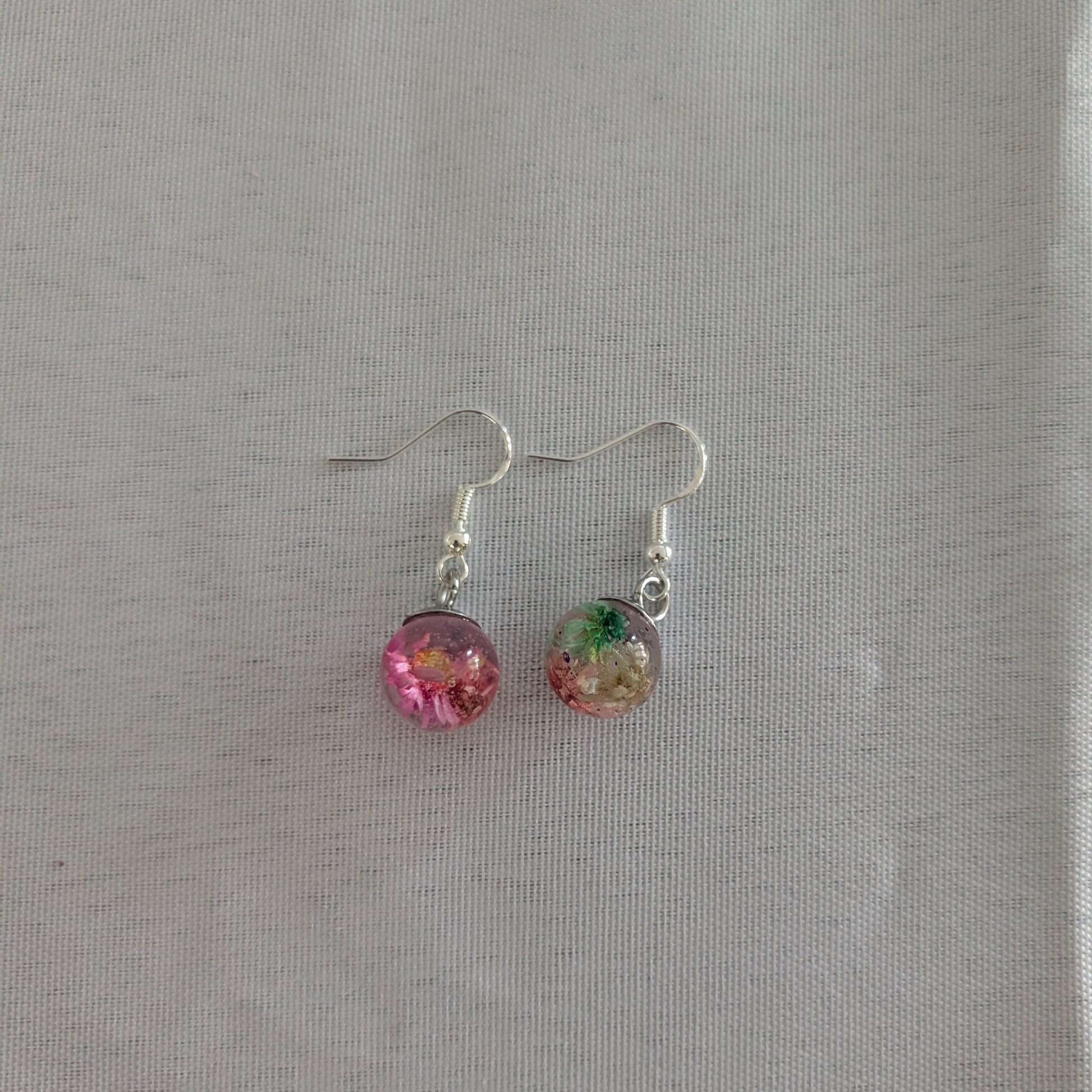 Pair of earrings with colorful beads on a gray background