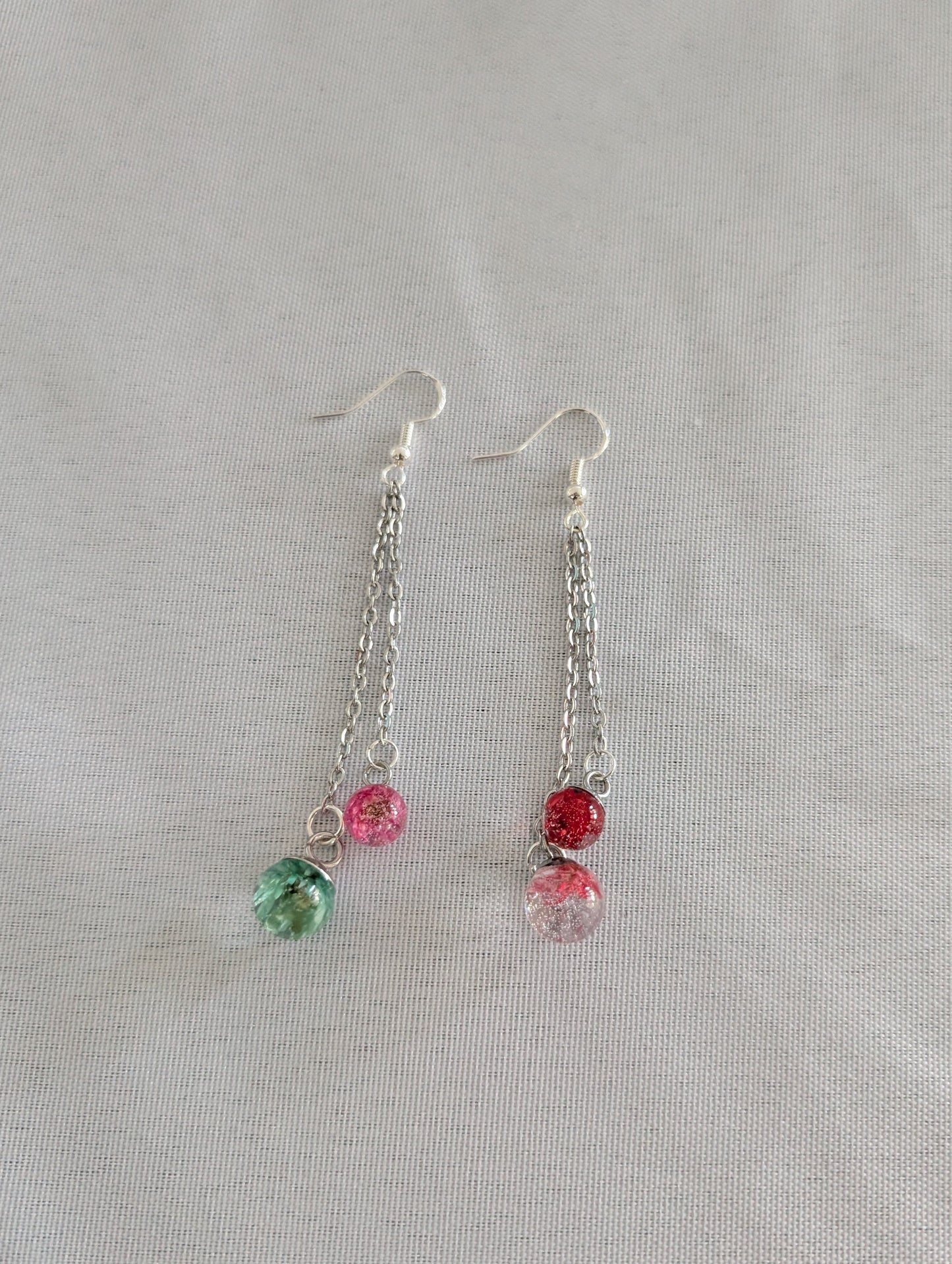 Pair of earrings with colorful beads on a light gray background