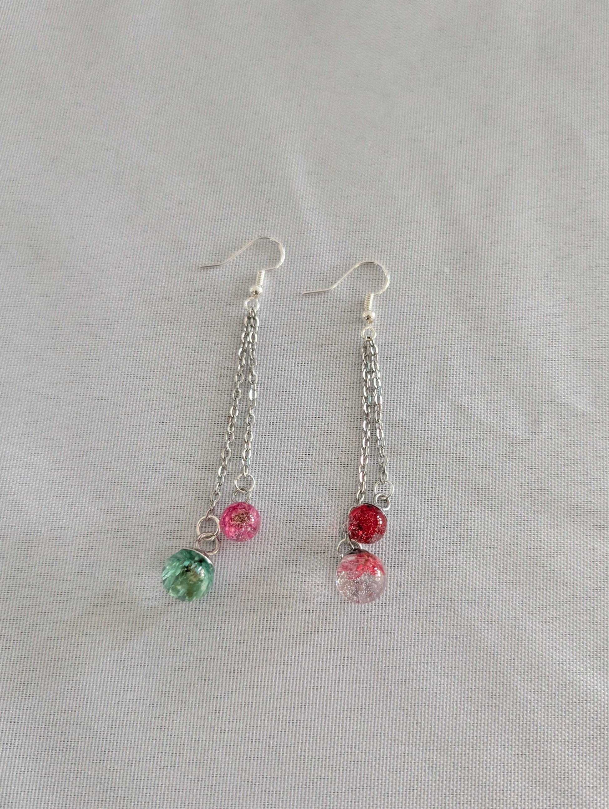 Pair of earrings with colorful beads on a light gray background