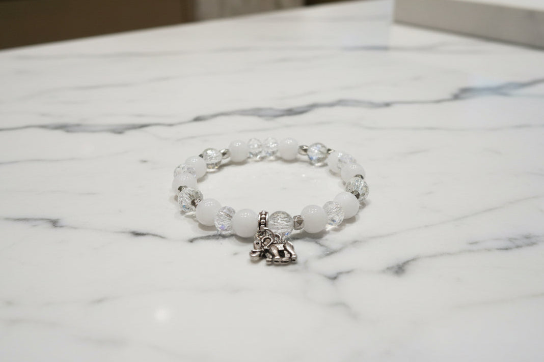 Celebrate wisdom and grace with this luminous elastic bracelet featuring a charming silver elephant charm. Strung with 8mm white and clear beads that sparkle with crystal and glass accents, complemented by delicate silver spacers, this piece radiates understated elegance. The elastic design stretches to fit comfortably on any wrist—no clasps needed—making it perfect for everyday wear or stacking with your favorite bracelets. At just 0.50 oz, it's lightweight enough to wear all day without fatigue. Whether y