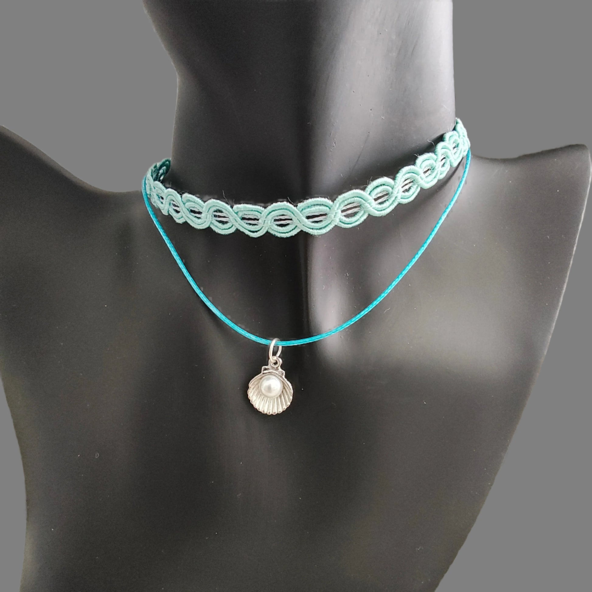Elevate your style with our stunning Choker Necklace! The aqua lace ribbon, paired with a delicate polyester strand, creates a unique and elegant look. Adorned with a charming clam shell and an acrylic white pearl bead, this necklace exudes sophistication and grace. Stand out from the crowd with this must-have accessory.